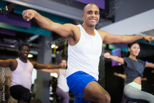 Man with others doing step aerobics in a fitness club
