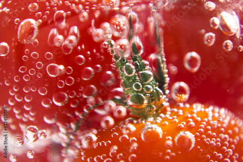 Red tomatoes in soda water with bubbles