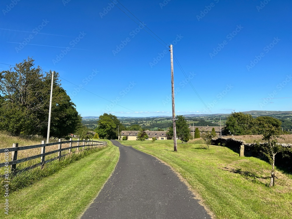 Smalden Lane, with grass verges, old stone buildings, and distant hills in, Grindleton, Clitheroe, UK Smalden Lane, with grass verges, old stone buildings, and distant hills in, Grindleton, Clitheroe, UK