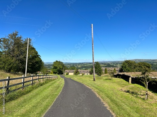 Smalden Lane, with grass verges, old stone buildings, and distant hills in, Grindleton, Clitheroe, UK