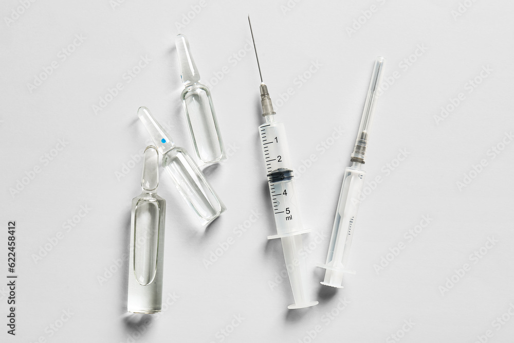 Medical ampules with syringes on light background Medical ampules with syringes on light background
