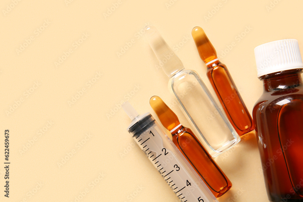 Ampules, bottle with medicines and syringe on beige background Ampules, bottle with medicines and syringe on beige background