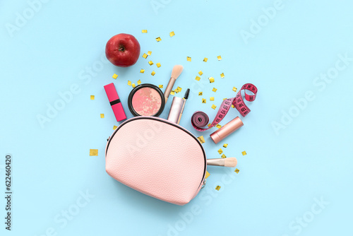 Composition with cosmetics, measuring tape and apple on blue background