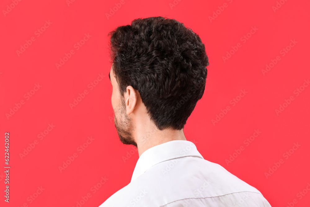 Young brunette man with stylish hairdo on red background, closeup Young brunette man with stylish hairdo on red background, closeup