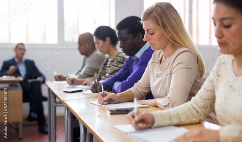 Young woman sitting at desk in classroom working during lesson at adult education class