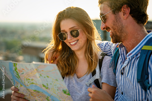 Happy couple on vacation sightseeing city with map. People travel fun love concept.