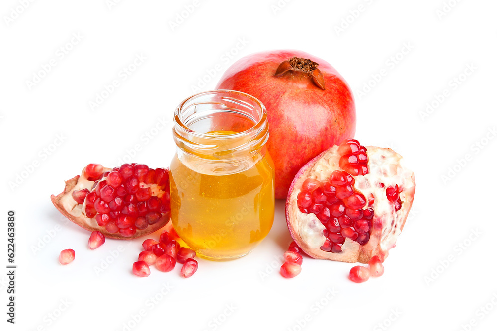 Jar of honey and ripe pomegranates on white background. Rosh hashanah (Jewish New Year) celebration Jar of honey and ripe pomegranates on white background. Rosh hashanah (Jewish New Year) celebration