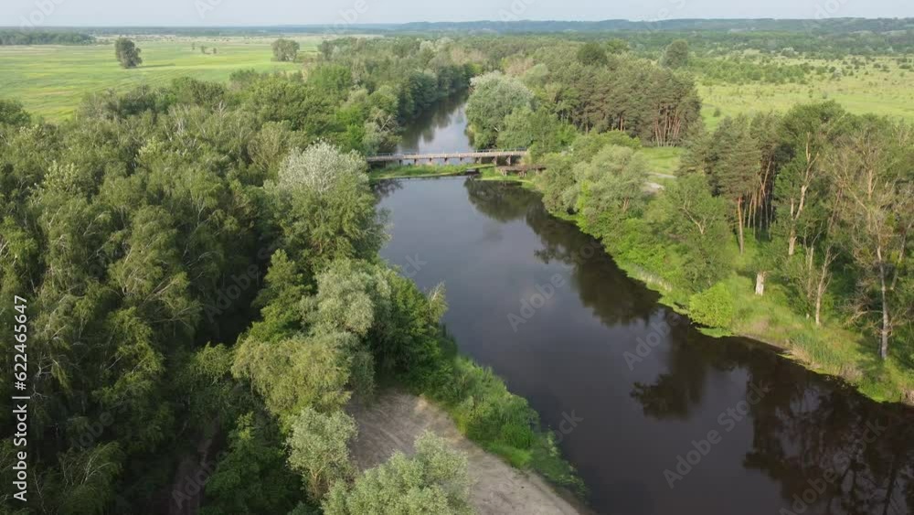 Drone view of the white river with a bridge among the trees. Shooting early in the morning in a temperate climate. Drone view of the white river with a bridge among the trees. Shooting early in the morning in a temperate climate.