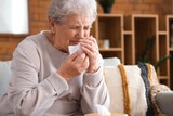 Ill senior woman with tissue at home, closeup