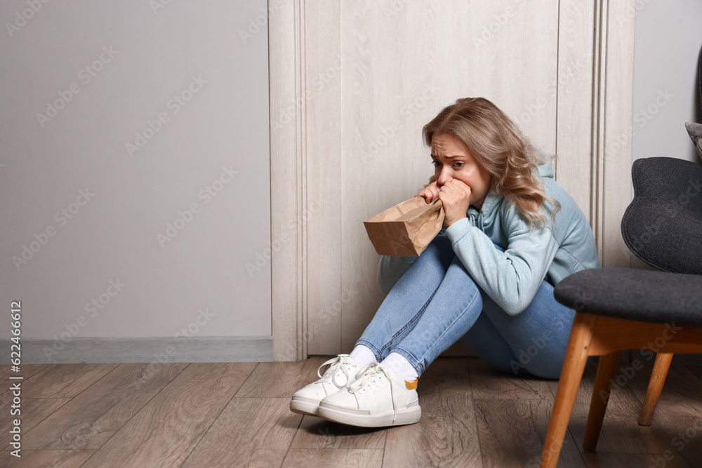 Young woman with paper bag having panic attack at home Young woman with paper bag having panic attack at home