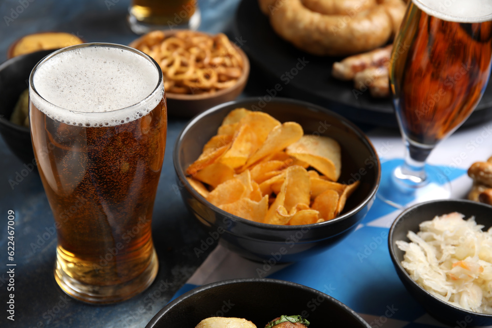 Glass of cold beer and snacks on blue background. Oktoberfest celebration Glass of cold beer and snacks on blue background. Oktoberfest celebration