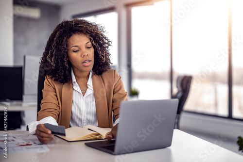 African -American woman typing credit card information on laptop