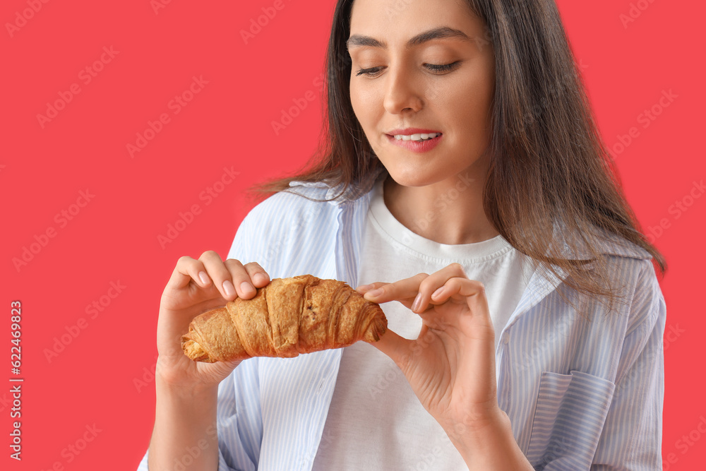 Young woman with tasty croissant on red background, closeup Young woman with tasty croissant on red background, closeup