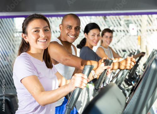 People having running elliptical trainer class in health club