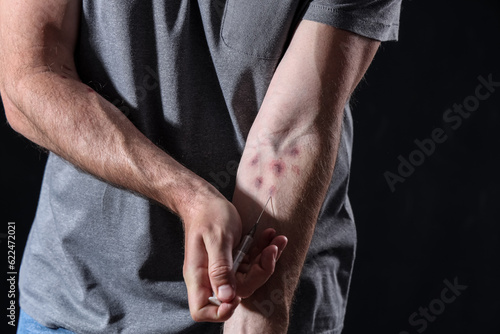 Male drug addict making injection on black background, closeup © Pixel-Shot