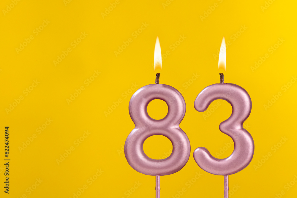 Candle 83 with flame - Birthday card on yellow luxury background Candle 83 with flame - Birthday card on yellow luxury background