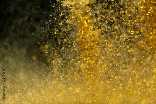 Explosion metallic gold glitter sparkle. Golden Glitter powder spark blink celebrate, blur foil explode in air, fly throw gold glitters particle. Black background isolated, selective focus Blur bokeh © Jade