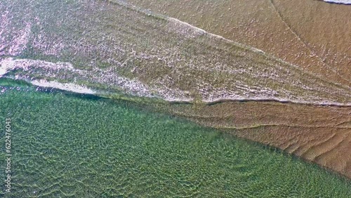 Waves crashing together over sandy beach