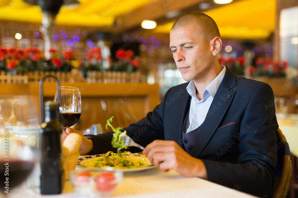Portrait of young elegant businessman having dinner in cozy restaurant alone