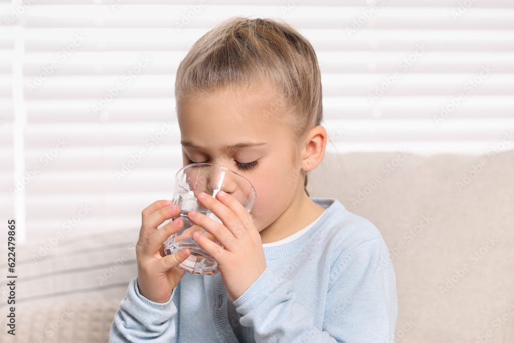 Cute little girl drinking fresh water from glass indoors Cute little girl drinking fresh water from glass indoors