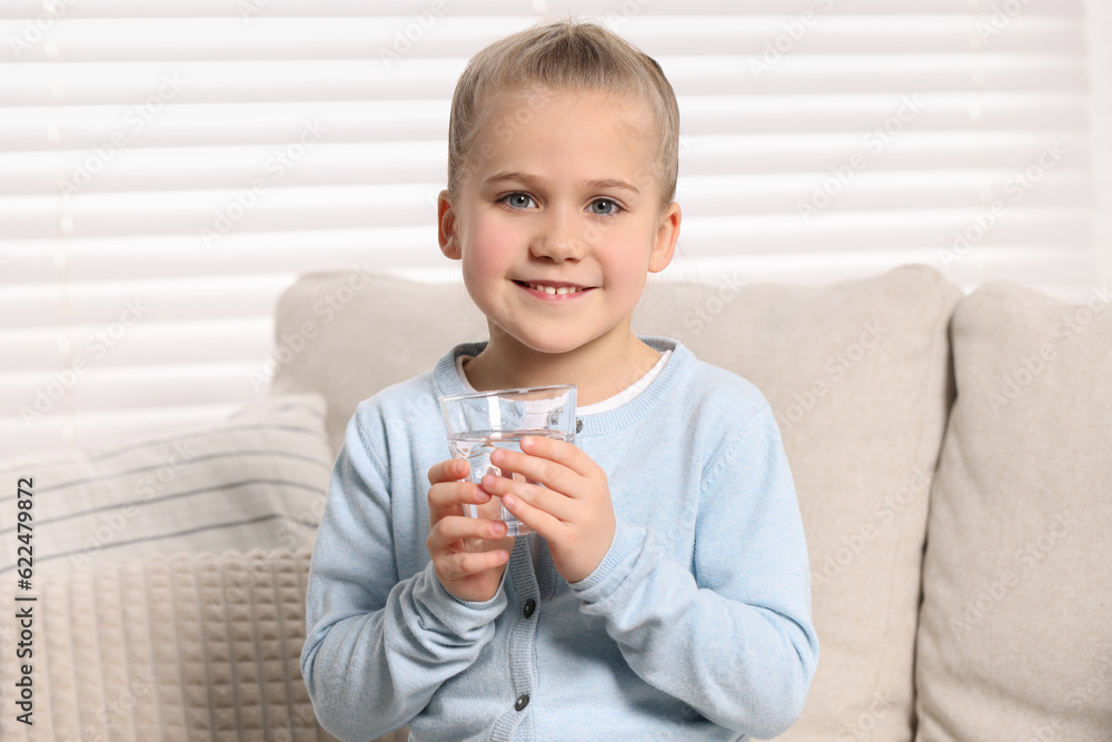 Happy little girl holding glass of fresh water indoors Happy little girl holding glass of fresh water indoors