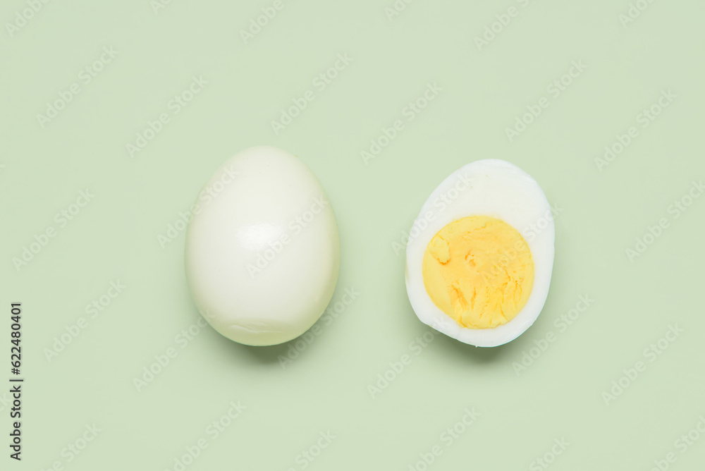 Tasty boiled egg with half on green background