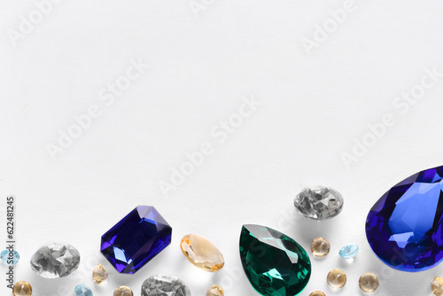 Different beautiful gemstones for jewelry on white background, top view. Space for text