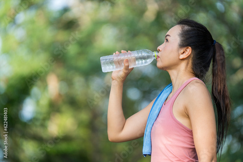 Healthy woman drinks water after workouts running exercise in the park in summer