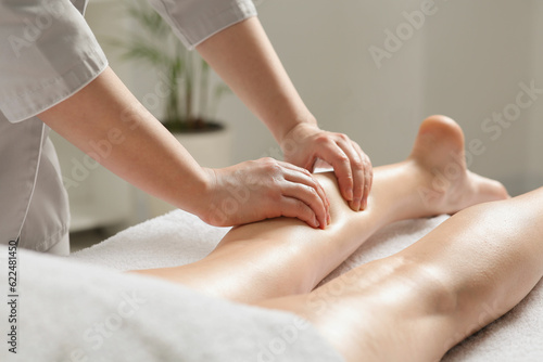 Woman receiving leg massage in spa salon, closeup photo