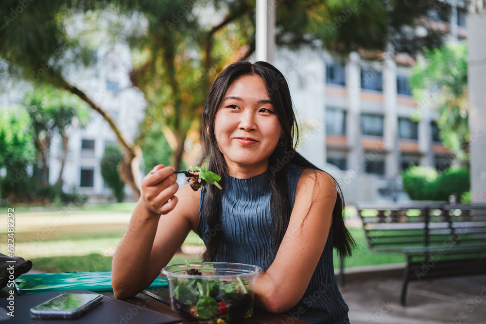 © Pablo Rasero - Smiling college student girl eating a healthy salad while taking a break with her friends © Pablo Rasero - Smiling college student girl eating a healthy salad while taking a break with her friends