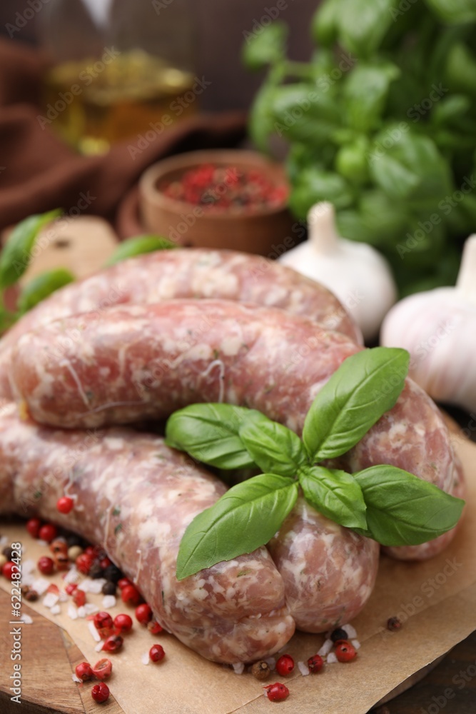 Raw homemade sausages and different spices on wooden board, closeup Raw homemade sausages and different spices on wooden board, closeup