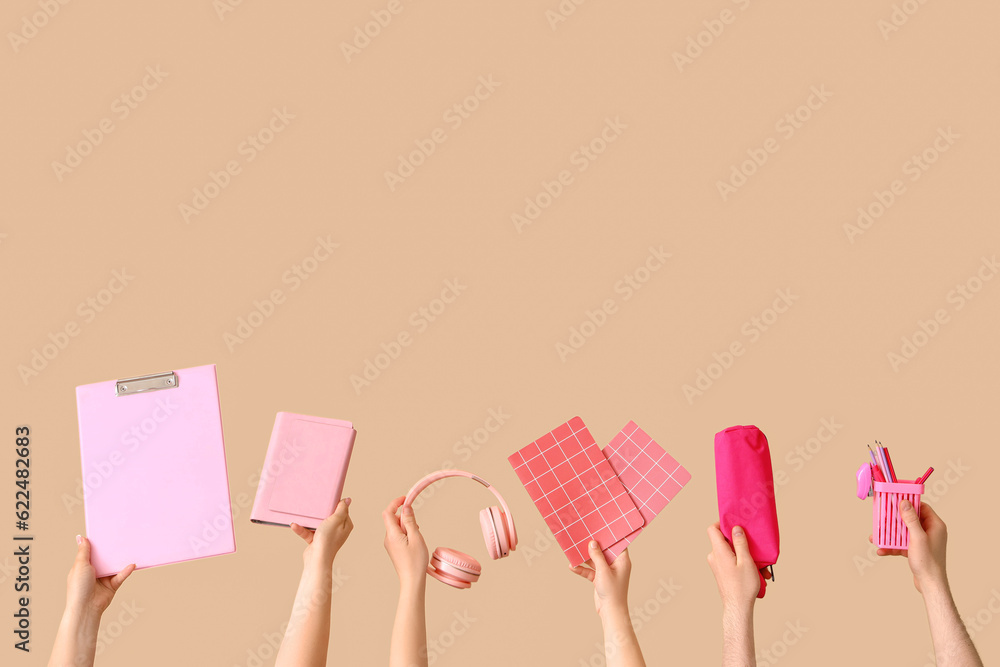Many hands holding school supplies on beige background Many hands holding school supplies on beige background