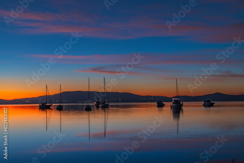Beautiful sunrise waterscape with high cloud, reflections and boats