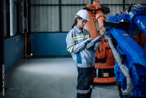 Quadro em tela Robotic technician uses control panel to operate, maintain robotic arm in factory