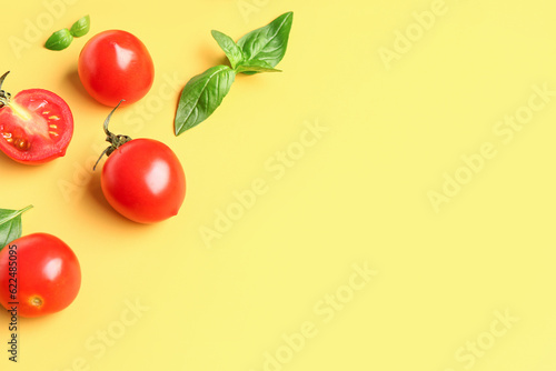 Fresh cherry tomatoes and basil on yellow background