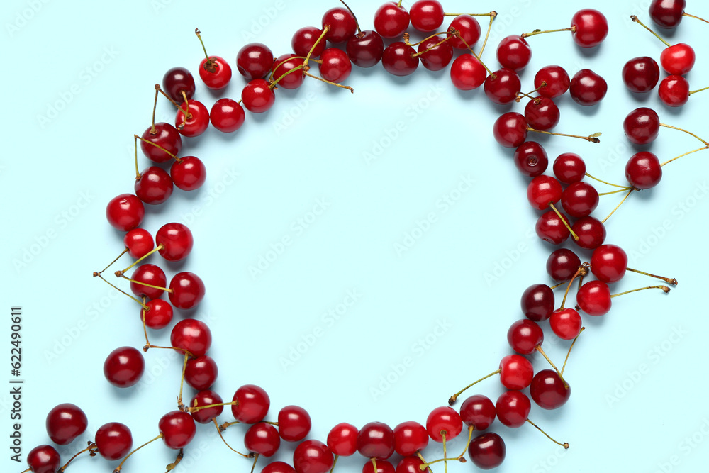 Frame made of red sweet cherries on blue background Frame made of red sweet cherries on blue background