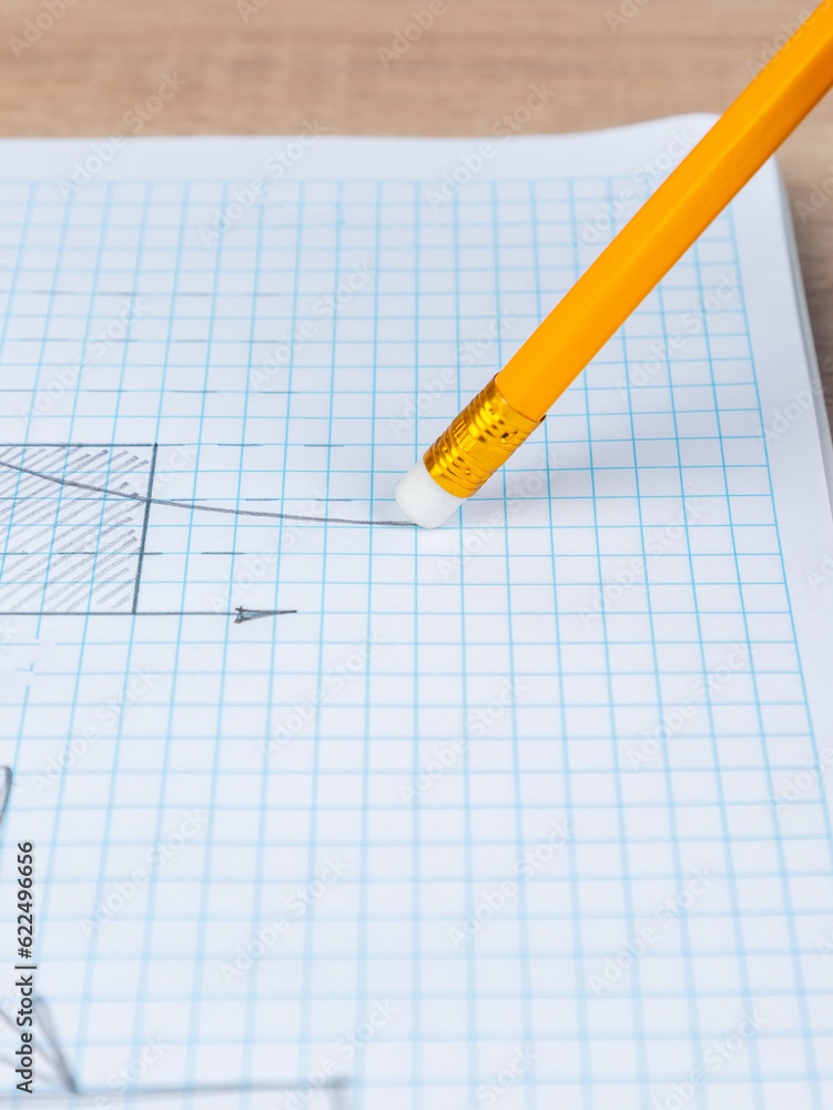 Close-up woman erasing a graph with a white rubber band on a slate pencil in a checkered notebook Close-up woman erasing a graph with a white rubber band on a slate pencil in a checkered notebook