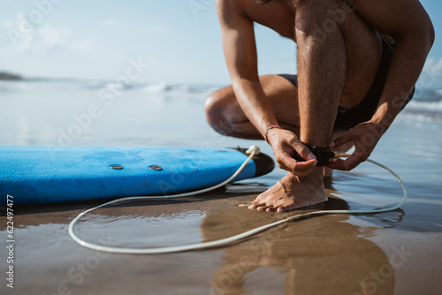 Photography close up of a man putting butts on his feet for safety before surfing at the bea