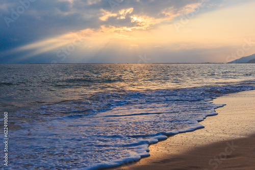 Sunset on the Sanya beach  the sun shines through the clouds on the golden sea and beach