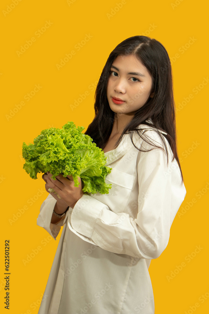 Vegetarian concept, Healthy woman eating fresh lettuce for diet food on isolated yellow background Vegetarian concept, Healthy woman eating fresh lettuce for diet food on isolated yellow background