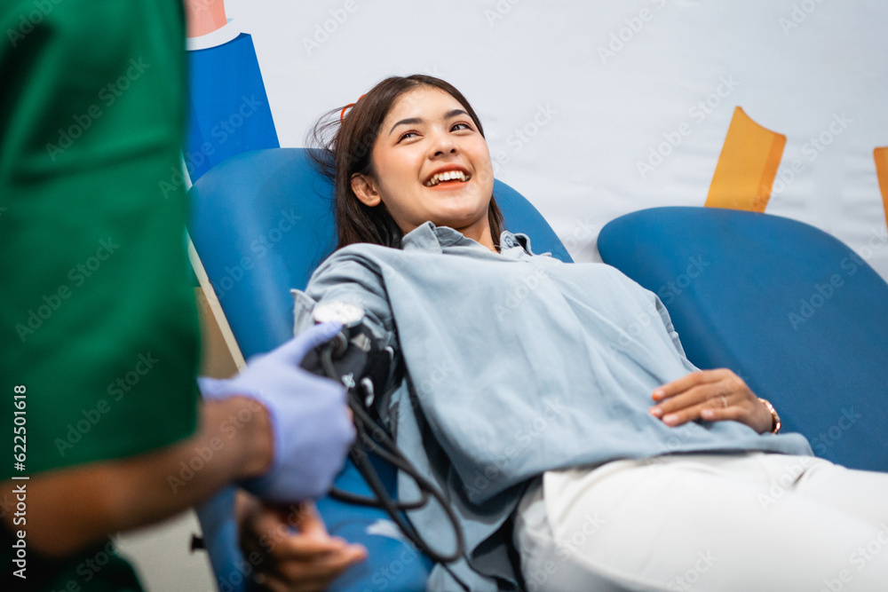 Obraz premium attractive young woman lying down with a tensimeter check by a doctor during a blood transfusion
