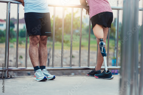 Friend support Friend with a prosthetic leg while exercising outdoor. People walking together on park outdoor. Exercise walking woman with prosthetic leg and friend support together in park outdoor