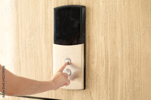 Woman finger pressing a up button of elevator button inside the building.