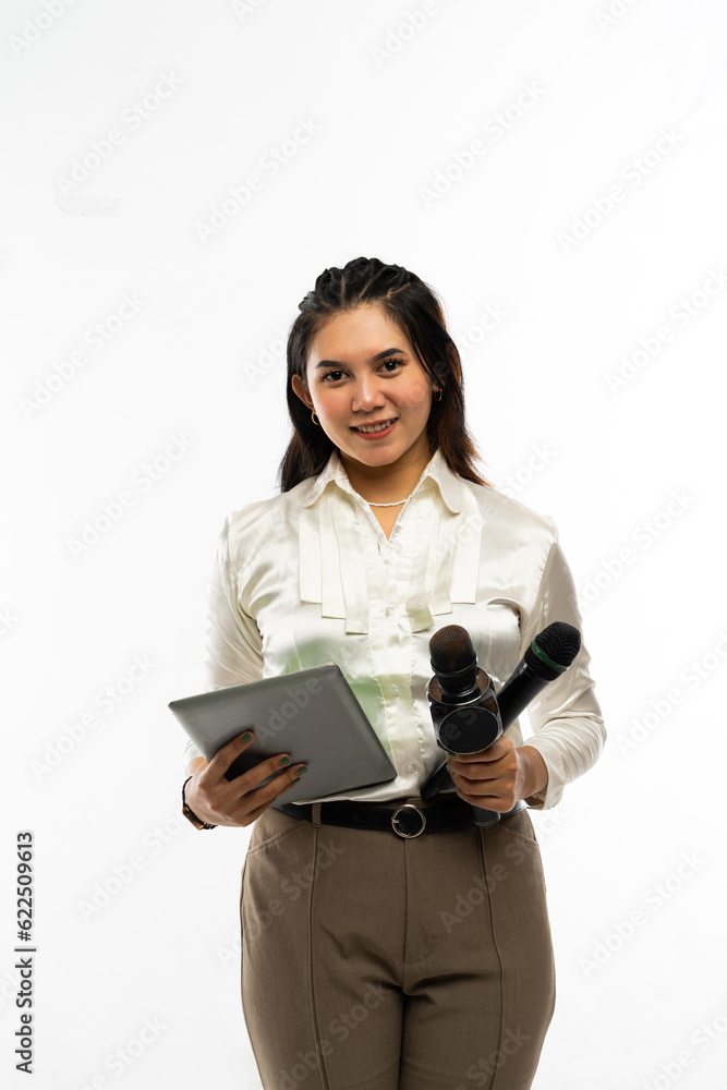 a female journalist with formal dressed standing bring two microphone and one tablet at her hand and smiling a female journalist with formal dressed standing bring two microphone and one tablet at her hand and smiling