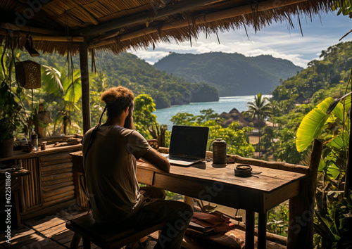 A digital nomad man working remotely in the tropic over looking the mountain and sea