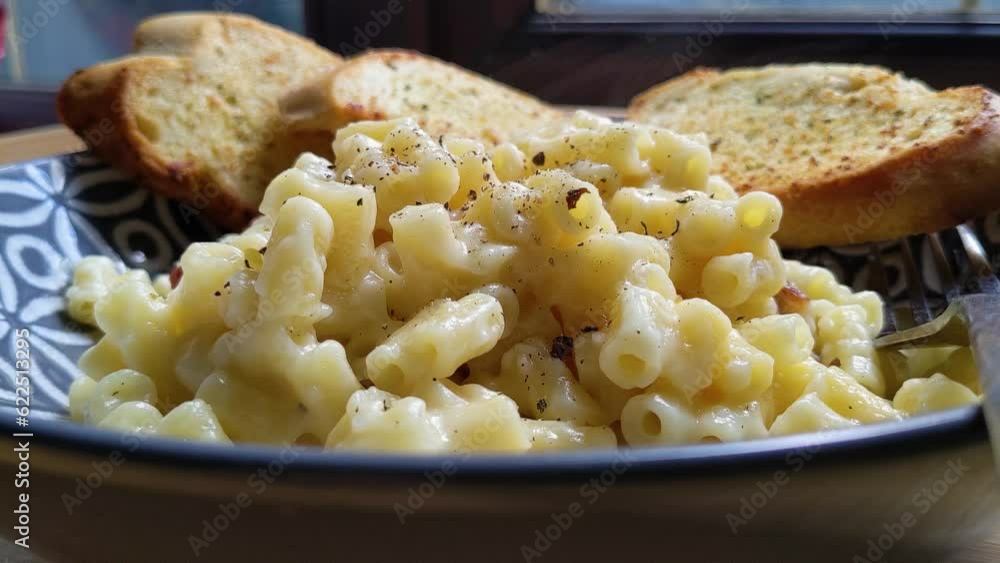 Plated Macaroni Cheese with Garlic Bread and Cracked Black Pepper Plated Macaroni Cheese with Garlic Bread and Cracked Black Pepper