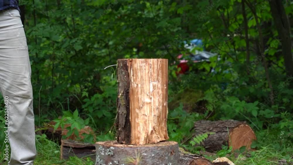 slow motion shot of a man in a flannel shirt splitting a log into quarters with an axe while camping slow motion shot of a man in a flannel shirt splitting a log into quarters with an axe while camping