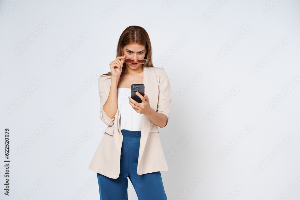 Businesswoman holding a phone while standing isolated on white background. Businesswoman holding a phone while standing isolated on white background.