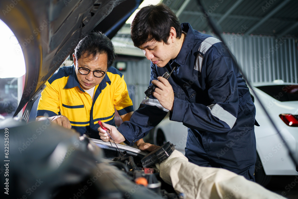 Team of vehicle technicians checking and measuring a vehicle oil engine or engine lubricant level by using oil stick indicator. 