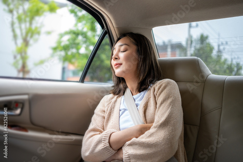 Relaxing moment of beautiful woman sleeping in car back seats with safety belt. Female happy in car while traveling on the road to your destination.a